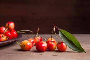 Kil plaka üzerinde vintage ahşap adam kiraz ağacının yaprak yeşil ile sarı tatlı kiraz ve çeşitli meyve çilek ile