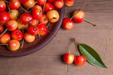 Kil plaka üzerinde vintage ahşap adam kiraz ağacının yaprak yeşil ile sarı tatlı kiraz ve çeşitli meyve çilek ile