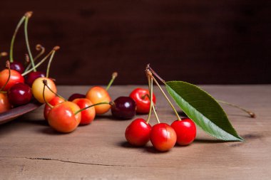 Kil plaka üzerinde vintage ahşap adam kiraz ağacının yaprak yeşil ile sarı ve kırmızı tatlı kiraz ve çeşitli meyve çilek ile