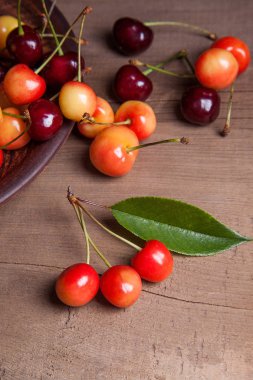 Kil plaka üzerinde vintage ahşap adam kiraz ağacının yaprak yeşil ile sarı ve kırmızı tatlı kiraz ve çeşitli meyve çilek ile