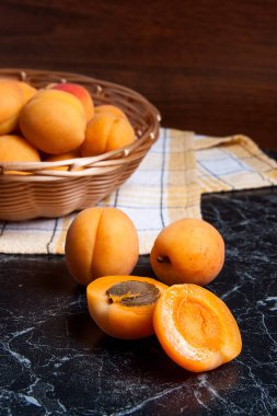 Olgun organik kayısı sarı ahşap sepet içinde. Rustik tarzı - organik kırmızı sulu kayısı karanlık mermer zemin üzerine vintage ahşap sepet içinde kompozisyon. Sağlıklı gıda kavramı. Hasat zamanı