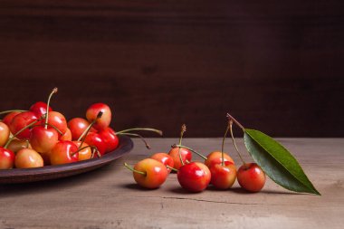 Kil plaka üzerinde vintage ahşap adam kiraz ağacının yaprak yeşil ile sarı tatlı kiraz ve çeşitli meyve çilek ile