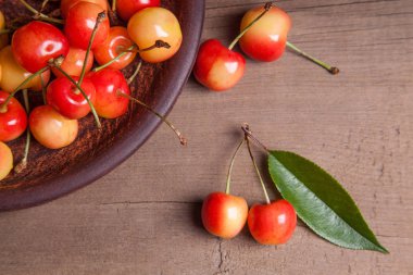 Kil plaka üzerinde vintage ahşap adam kiraz ağacının yaprak yeşil ile sarı tatlı kiraz ve çeşitli meyve çilek ile