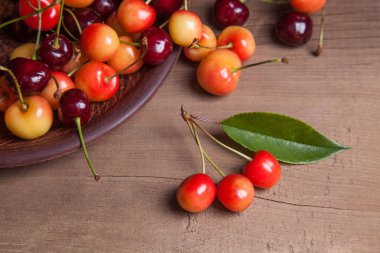 Kil plaka üzerinde vintage ahşap adam kiraz ağacının yaprak yeşil ile sarı ve kırmızı tatlı kiraz ve çeşitli meyve çilek ile