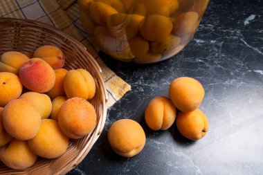 Tatlı Kayısı Kompostosu karanlık mermer üzerinde büyük cam kavanoz konserve ve yaz anda olgun organik kayısı hasat. Rustik tarzı - organik sarı sulu kayısı bütün ve yarıya sarı ahşap sepet ve ev yapımı Kayısı Kompostosu canne kompozisyon