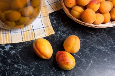 Tatlı Kayısı Kompostosu karanlık mermer üzerinde büyük cam kavanoz konserve ve yaz anda olgun organik kayısı hasat. Rustik tarzı - organik sarı sulu kayısı bütün ve yarıya sarı ahşap sepet ve ev yapımı Kayısı Kompostosu canne kompozisyon