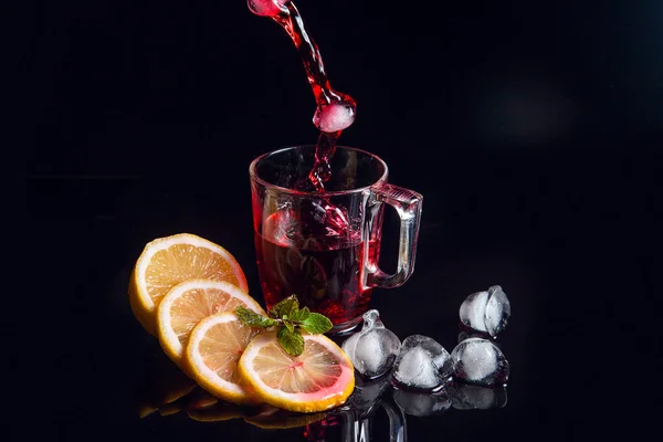 Hibiscus cold tea pouring into glass with ice, lemon and mint is — Stock Photo, Image