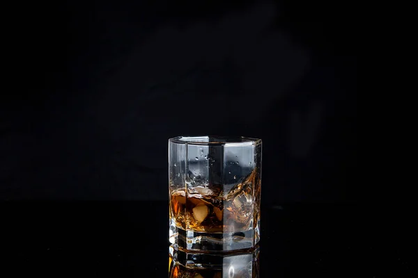 Whiskey splash from the fallen ice cube into glass with beverage — Stock Photo, Image