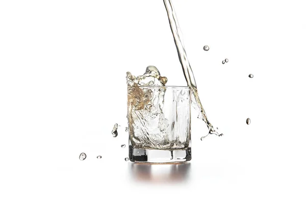 Whiskey pouring into glass with ice on light background — Stock Photo, Image