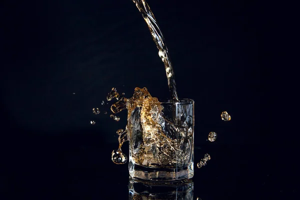 Siyah arka plan üzerine izole buzlu cam içine dökme viski