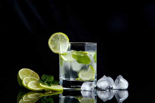 Летний коктейль мохито в стакане, нарезанный лайм и кубики льда на bl — стоковое фото