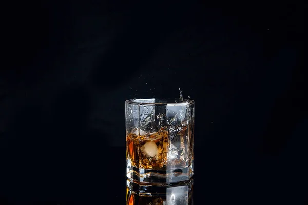 Whiskey splash do cubo de gelo caído em vidro com bebida — Fotografia de Stock