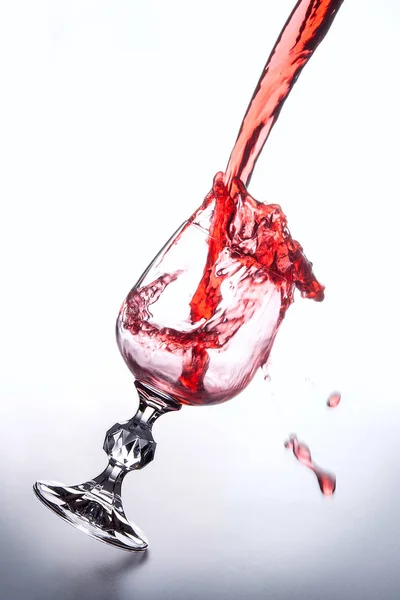 Rotwein in ein Weinglas auf hellem Hintergrund gießen. — Stockfoto