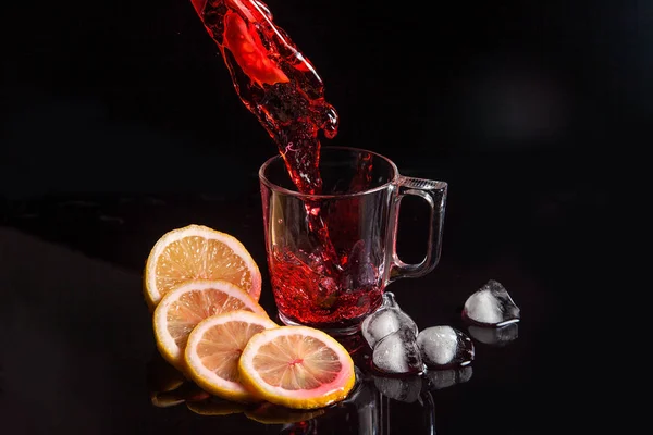 Hibisco chá frio derramando em vidro com gelo, limão e hortelã é — Fotografia de Stock