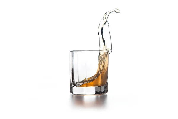 Whisky plons in glas met ijs op lichte achtergrond — Stockfoto