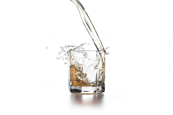 Whisky verser dans le verre avec de la glace sur fond clair — Photo