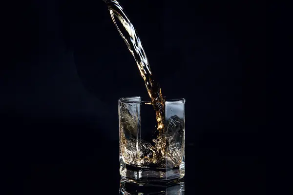 Whisky im Glas mit Eis isoliert auf schwarzem Hintergrund — Stockfoto