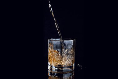 Siyah arka plan üzerine izole buzlu cam içine dökme viski