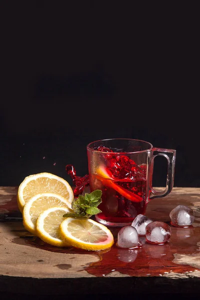 Hibiscus cold tea splash from the fallen slice of lemon into gla
