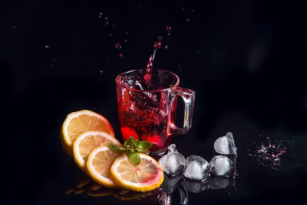 Hibiscus salpicadura de té frío del cubo de hielo caído en el ingenio de vidrio — Foto de Stock