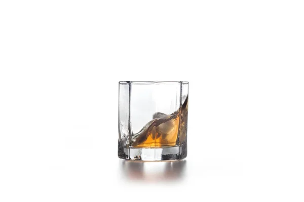 Whiskey splash in glass with ice on light background — Stock Photo, Image