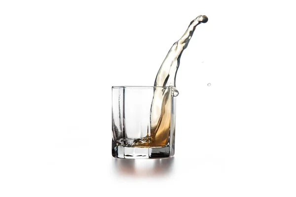 Whiskey splash in glass with ice on light background — Stock Photo, Image