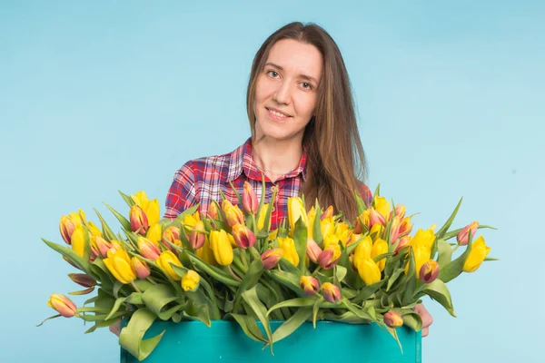 Jovem florista alegre segurando caixa de tulipas . — Fotografia de Stock