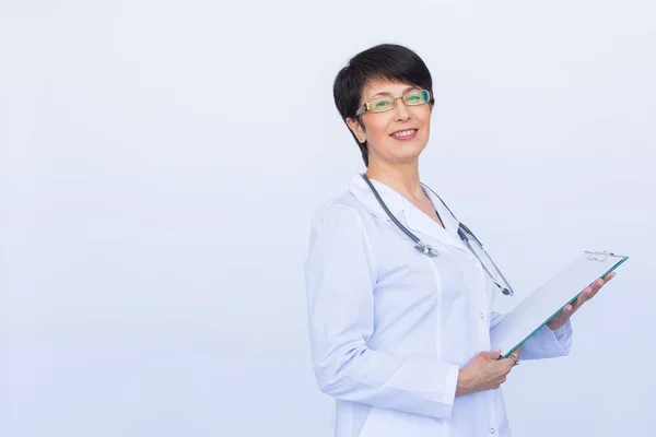 Retrato de médico feminino escrevendo na área de transferência sobre um fundo branco com espaço de cópia — Fotografia de Stock