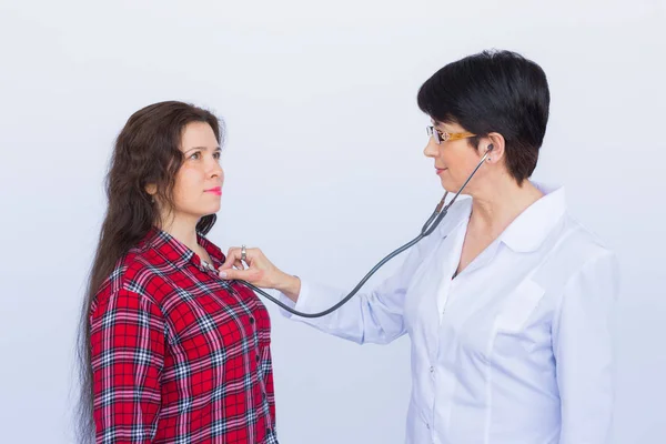 healthcare, medical exam, people and medicine concept - young woman and doctor with stethoscope listening to heartbeat over white background