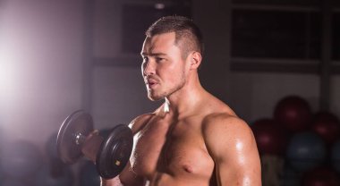 kas genç adam koyu arka plan üzerinde ağırlık kaldırma