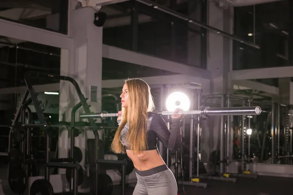 Vacker kvinna träna med skivstång i ett gym — Stockfoto