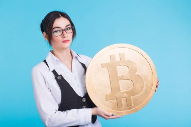 Gözlüklü genç başarılı kendine güvenen kadın büyük bir bitcoin elinde tutar.