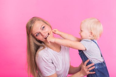 mutlu küçük kız ve annesi pembe arka plan üzerinde eğleniyor