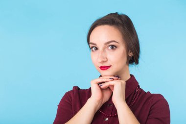 Temiz cilt, doğal makyaj ve mavi arka plan üzerinde kırmızı dudaklar ile gülümseyen güzel kadın