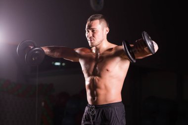 Yakışıklı güç dumbbell atletik adamla. Altı paket, mükemmel abs, omuzlar, pazı, triceps ve göğüs ile güçlü vücut geliştirmeci