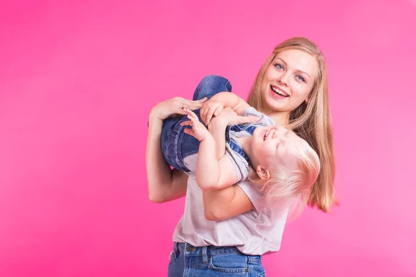Familia divertida sobre fondo rosa. Madre y su hija. Mamá y el niño se están divirtiendo . — Foto de Stock