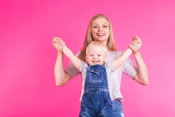 Menina feliz e sua mãe se divertindo sobre fundo rosa — Fotografia de Stock