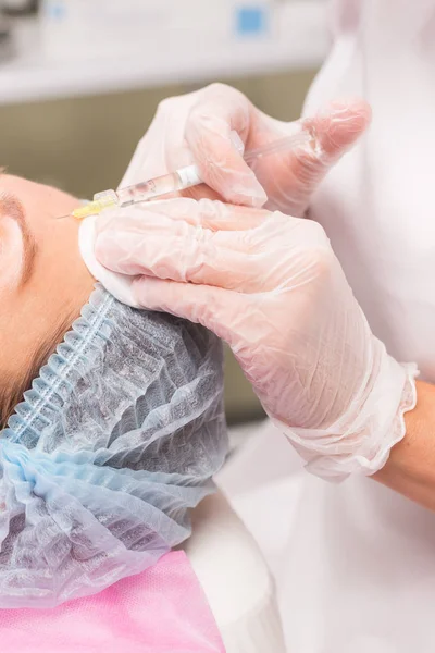 Close-up de mãos de esteticista especialista injetando na testa feminina — Fotografia de Stock