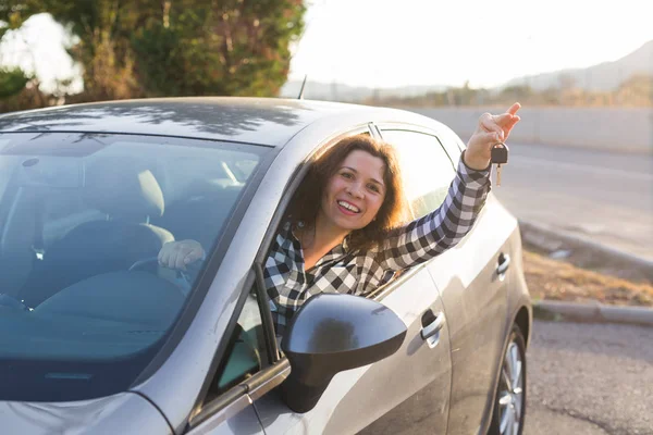 Junges lächelndes Mädchen sitzt am Steuer eines Autos und hält Schlüssel in der Hand — Stockfoto