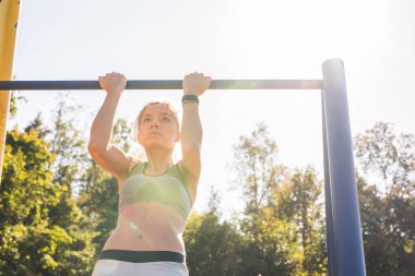 Barfiks çekmek açık spor zeminde yapıyor genç güzel kız