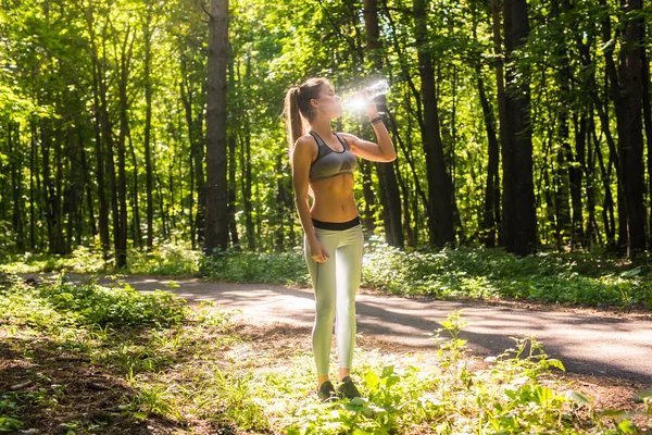 Mujer joven bebiendo agua después de correr al aire libre — Foto de Stock