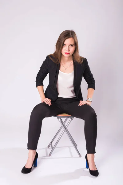 Caucasian attractive female model with brunette hair posing in studio, wearing formal suit isolated on white background