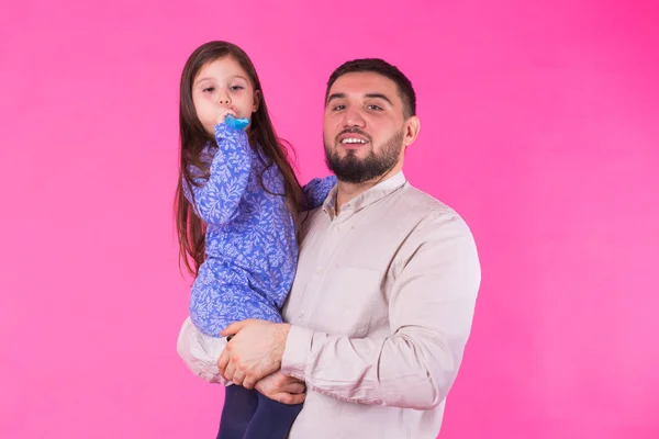 Feliz padre sosteniendo bebé hija en manos sobre rosa fondo — Foto de Stock