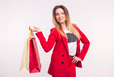 Beyaz arka plan üzerinde alışveriş torbaları ile sarışın genç çilli kadın portresi