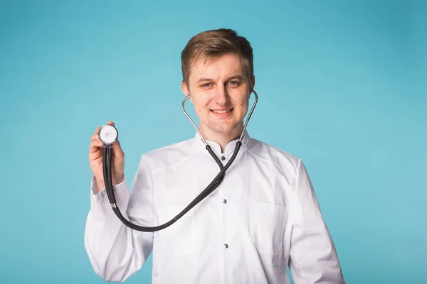 Lekarz z stetoskop Wyświetlono kciuk w na niebieskim tle — Zdjęcie stockowe