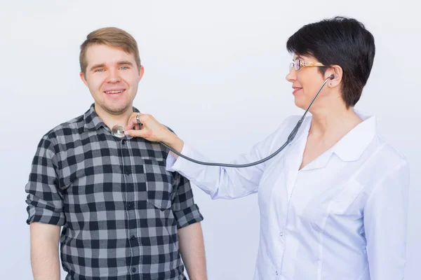 Ο γιατρός ακούει χαρούμενα νέους ασθενείς θώρακα με στηθοσκόπιο πάνω από το λευκό φόντο — Φωτογραφία Αρχείου