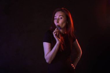 Genç kadın sigara elektronik sigara koyu arka plan üzerinde