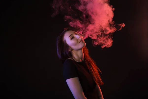 Jovem mulher fumar cigarro eletrônico no fundo escuro — Fotografia de Stock