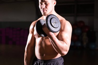 Yakışıklı güç dumbbell atletik adamla. Altı paket, mükemmel abs, omuzlar, pazı, triceps ve göğüs ile güçlü vücut geliştirmeci