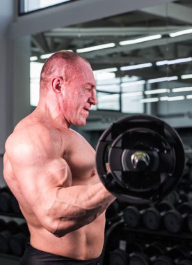 Spor salonunda yakışıklı vücut geliştirmeci adamla büyük kaslar